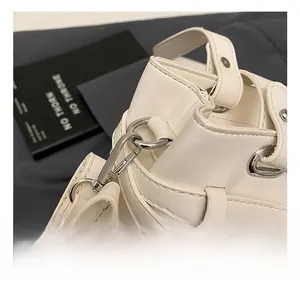 Detail shot of silver metal hook and strap connector on a white lychee grain handbag