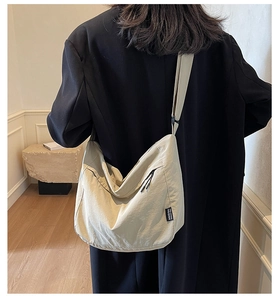 Dettaglio borsa a tracolla beige con tracolla regolabile sopra un blazer nero
