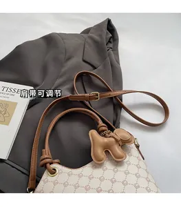 Détail du sac seau imprimé avec bandoulière réglable et accessoire de charme chiot 3D