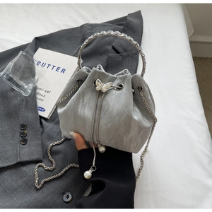 Détail du sac seau gris avec breloque papillon, perles et poignée anneau en strass