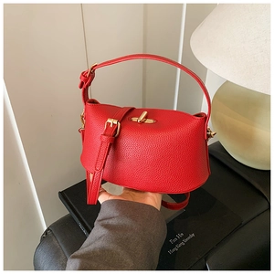 Detail der roten Handtasche mit Lychee-Maserung, goldenem Schloss und Schultergurt