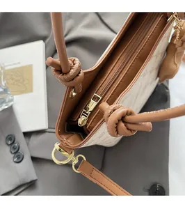 Détail de la fermeture éclair dorée et de la poignée en cuir noué du sac seau élégant
