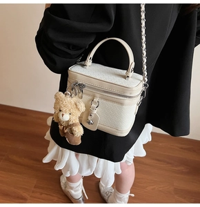 Détail du sac boîte en cuir tressé blanc avec chaîne argentée et breloque ours en peluche