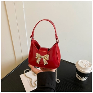Détail du mini sac en cuir verni rouge avec fermoir nœud doré et bandoulière chaîne