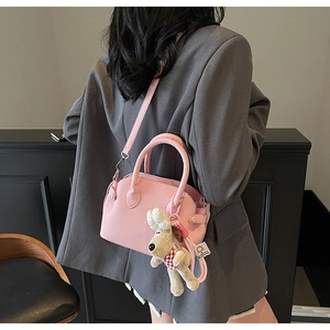 Pink lychee grain shell bag with cute puppy plush charm and adjustable shoulder strap