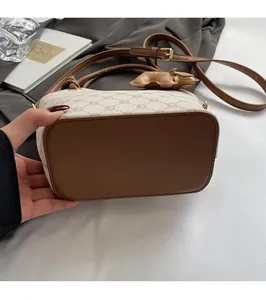 Détail de la base en cuir marron renforcé et du charm floral sur le sac seau à motif