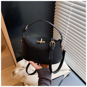 Detail einer schwarzen Handtasche aus Leder mit goldener Schließe und Tragegriff