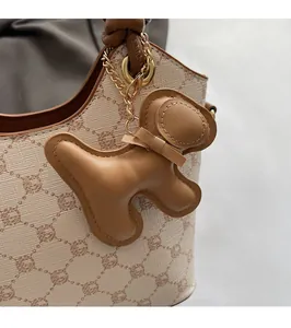 Détail d'un bijou de sac en cuir en forme de chien avec nœud et chaîne dorée chic