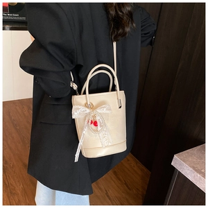 Détail du sac seau crème avec nœud en dentelle et breloques cerises en perles