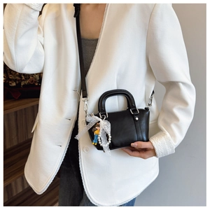 Detail of black faux leather doctor bag with lace bow charm and pearl handle detail