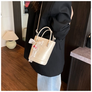 Sac seau beige avec nœud en dentelle porté par un mannequin dans un intérieur chic