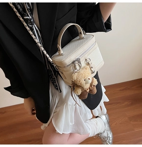 Détail du sac bowling crème tissé avec un charm ours en peluche et bandoulière chaîne