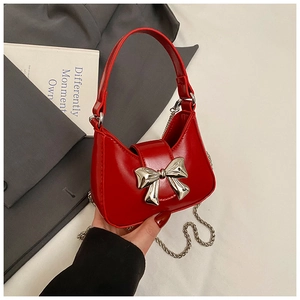 Gros plan détaillé d'un mini sac rouge brillant avec boucle nœud argentée et chaînette