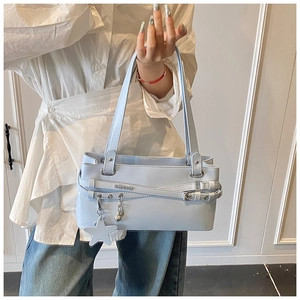 Détail du sac sous le bras bleu clair avec boucles et breloques cœur et étoile