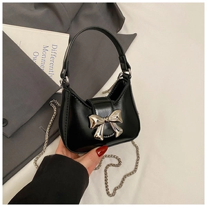 Détail d'un mini sac à main noir orné d'un grand nœud argenté et d'une bandoulière chaîne