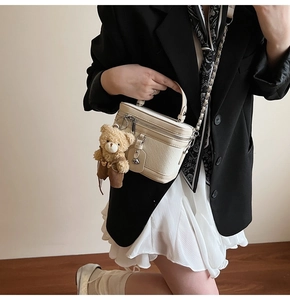 Vue détaillée du mini sac vanity crème avec matelassage en losanges et charme d'ours peluche