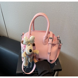 Detalle de bolso rosa con textura de grano y un lindo colgante de perro de peluche