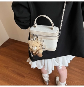 Détail d'un sac boîte blanc tressé avec un charm d'ours mignon et double fermeture éclair