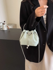 Sac seau vert menthe moderne avec fermoir papillon et pompon en perle sur un mannequin femme
