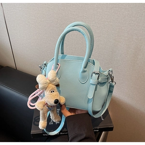 Detalle de bolso azul claro con textura de piel lichi y un tierno colgante de perrito