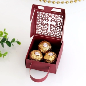Macro detail of wine red laser-cut candy box with ornate cross hollow pattern