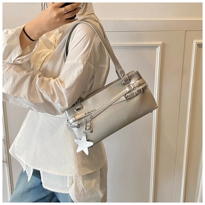 Détail d'un sac à bandoulière argenté avec lanière en cuir et pendentif étoile