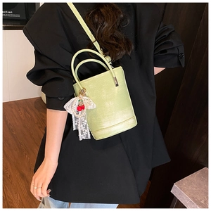 Détail du sac seau vert clair avec pendentifs cerises rouges et nœud en dentelle blanche