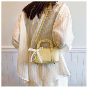 Light yellow mini leather bag with white lace bow and plush doll on a model back