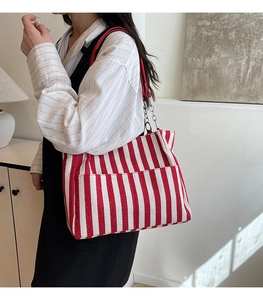 Détail du sac cabas en toile rayé rouge et blanc avec bandoulière chaîne sur modèle