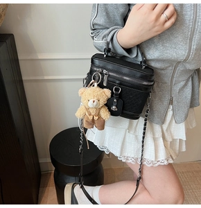Détail de la texture tressée sur le sac noir avec garniture argentée et ours en peluche