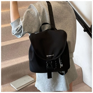 Dettaglio dello zaino in nylon nero con patta curva e chiusura con fibbia in plastica