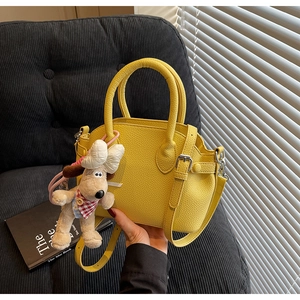 Detalle de bolso amarillo con grabado de lichi, peluche de Gromit y herrajes de plata