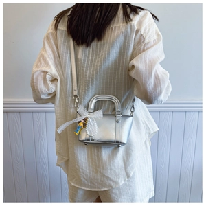 Silver mini handbag with white lace bow and doll charm shown on model back view