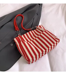 Détail du sac fourre-tout en toile rayé rouge et blanc avec poignées en cuir rouge