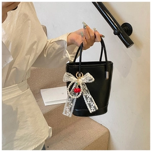 Détail du sac seau noir avec nœud en dentelle et breloque cerise avec perles