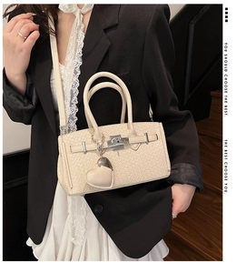 Detail of cream woven leather Kelly style bag with silver hardware and heart charm