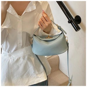 Nahaufnahme hellblaue Lederhandtasche mit Litschimuster, Goldverschluss und Schultergurt