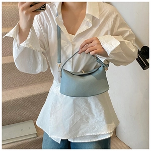 Detail der hellblauen Handtasche aus Leder mit Lychee-Muster und goldenem Drehverschluss