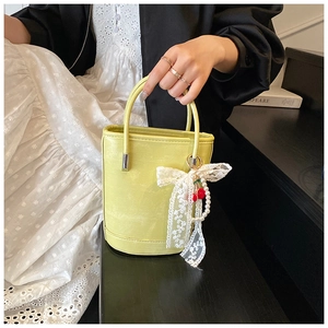 Détail du sac à main jaune avec nœud en dentelle, cerises et chaîne en perles