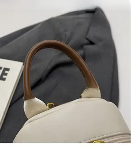 Gros plan détaillé sur le cuir beige grainé et la fermeture éclair dorée du sac à dos