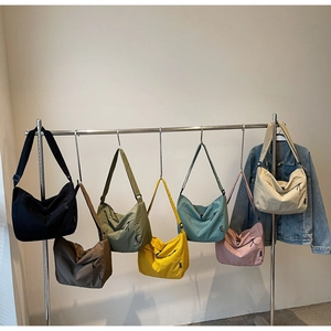 Collezione di borse a tracolla in nylon a mezzaluna colorate appese su grucce