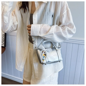 Silver metallic mini Boston bag with lace bow and pearl charm worn by model