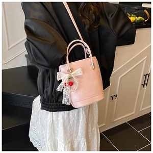 Sac seau rose avec nœud en dentelle blanche, charm cerise et détails en perles