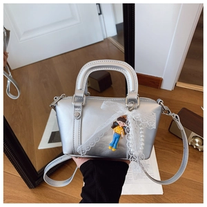 Detail of silver faux leather shoulder bag with white lace bow and cartoon charm