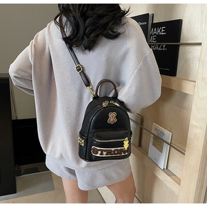 Détail du sac à dos en cuir PU noir avec écusson ours et rivets dorés élégants