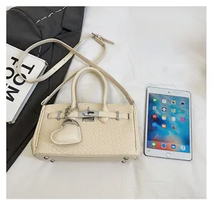 Detail of cream crocodile embossed bag with gold clasp shown next to an iPad for size comparison