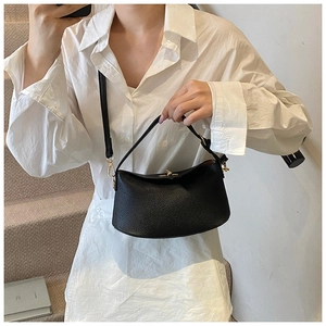 Detail einer schwarzen Lederhandtasche mit Lychee-Maserung und goldener Schließe