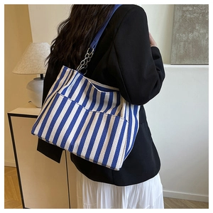 Détail du sac cabas en toile à rayures bleues avec bandoulière chic en chaîne et cuir