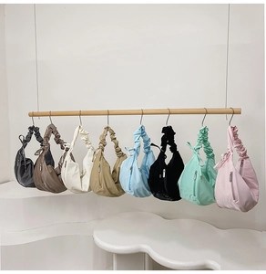 Row of colorful nylon crescent bags with ruched straps in eight candy colors on wooden rack