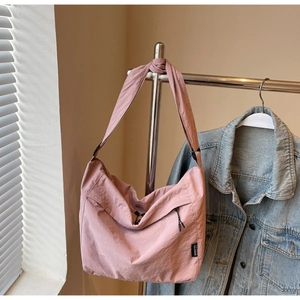 Dettaglio della grande borsa a tracolla in nylon rosa loto con tracolla regolabile e logo